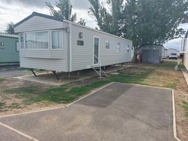 A static caravan with steps and windows at St Osyth Beach in Clacton-on-Sea
