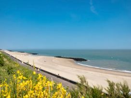 A beach with a path and people walking at St Osyth Beach in Clacton-on-Sea