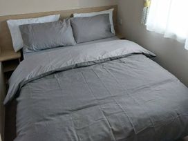 A bed with gray bedding and pillows at St Osyth Beach in St. Osyth