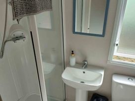 A bathroom featuring a shower, sink, toilet, and mirror at St Osyth Beach in St. Osyth