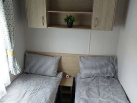 A bedroom with two beds and a shelf at St Osyth Beach in St. Osyth