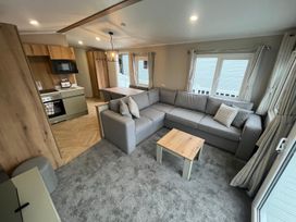 A living room with a sofa and kitchenette at Cala Gran - The Retreat 256 Boundary Road in Fleetwood