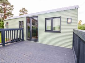 An outdoor view of a cabin with a deck and multiple windows at Calendonia Hut West Mains near Haggerston