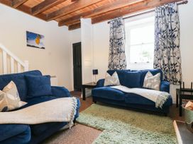 A living room with blue sofas and a decorative rug at Acorn in Cleator