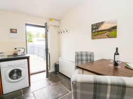 A kitchen with a washing machine, table, and chairs at Acorn in Cleator