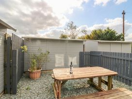 An outdoor area with a wooden table and a bottle on it at Acorn in Cleator