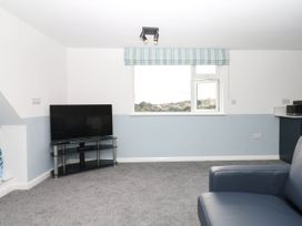 A living room with a TV and window at Merlins Hideaway in Dawlish