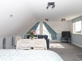 A loft with a bed and a seating area at Merlins Hideaway in Dawlish