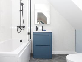 A bathroom with a bathtub and sink at Merlins Hideaway in Dawlish