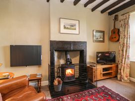 A living room with a fireplace and television at 2 High Moss House in Broughton-in-Furness