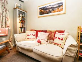 A living room with a sofa and bookshelf at 2 High Moss House in Broughton-in-Furness