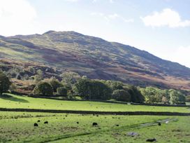 A landscape with cows grazing in a field and a mountain in the background at 2 High Moss House in Broughton-in-Furness