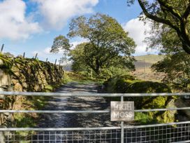 A gravel road with a gate and a sign at High Moss in Broughton-in-Furness