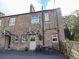 An outdoor view of a stone cottage with a table and chairs at The Gables in Alnwick