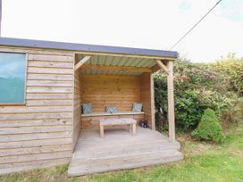 An outdoor seating area with a wooden cabin and bench at The Gables in Alnwick