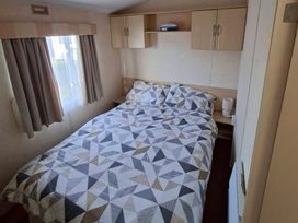 A bedroom with a bed and shelves at Golden Sands Haven, Sunflower Haven, Mablethorpe