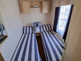 A bedroom with two beds and a stuffed animal at Golden Sands Haven, Sunflower Haven in Mablethorpe