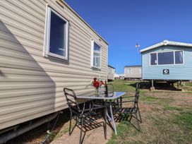 An outdoor table with chairs and flowers near trailers at Spruces 30 Sandy Bay, Exmouth