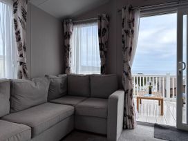 A living room with a sofa and view to a deck at Club Sahara, Sandy Bay, Exmouth