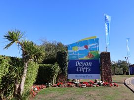 A sign for Devon Cliffs Holiday Park with plants and flowers in Sandy Bay, Exmouth