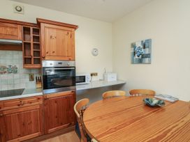 A kitchen with wooden cabinets and a round table at Willow in Kingsteignton