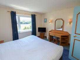 A bedroom with a bed, dresser, and television at Goldfinch in Kingsteignton