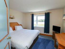 A bedroom with a bed, desk, and television at Teal in Kingsteignton