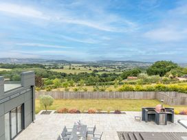 A patio area with a table and chairs overlooking the landscape at Huxham View & Annex in Kingsteignton