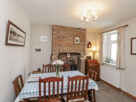 A dining room with a brick fireplace and wooden furniture at Chapel Cottage in Filey