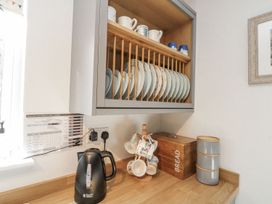 A kitchen with a kettle, plates on a rack, and a storage box at Chapel Cottage in Filey