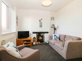 A living room with a sofa and television at Derwen-Las in Penmaenmawr