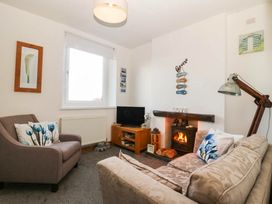 A living room with a sofa and television at Derwen-Las in Penmaenmawr