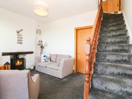A living room with a sofa and fireplace at Derwen-Las in Penmaenmawr