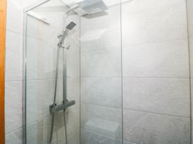 A shower with a glass panel and tiles at Derwen-Las in Penmaenmawr