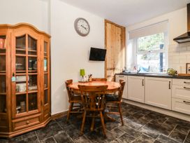 A kitchen with a dining table and display cabinet at Derwen-Las Penmaenmawr