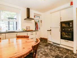 A kitchen with a round wooden table and appliances at Derwen-Las in Penmaenmawr