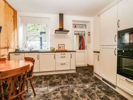 A kitchen with cabinets, a table, and a sink at Derwen-Las in Penmaenmawr