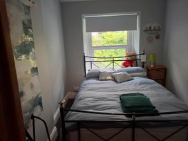 A bedroom with a metal bed and window view at Derwen-Las in Penmaenmawr