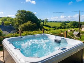 A hot tub on a wooden deck overlooking the countryside at The Retreat in Devon