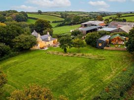 An outdoor view of a house with garden and outbuilding in an open field