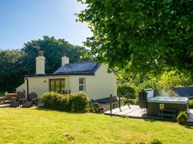 A cottage with hot tub and chairs in the garden at 