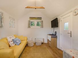 A snug with a yellow sofa, television, and table at The Old Barn in Manchester