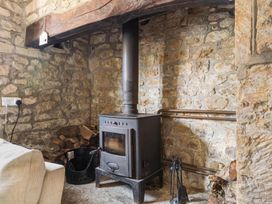 A living room with a wood-burning stove and stone walls at The Old Barn in Manchester