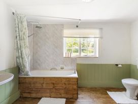 A bathroom with a bathtub, shower, toilet, and sink at The Old Barn in Manchester