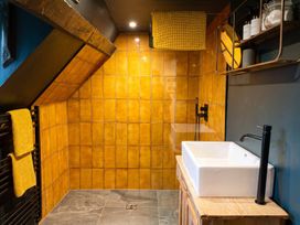 A bathroom with a shower, sink, and shelves at the property in location