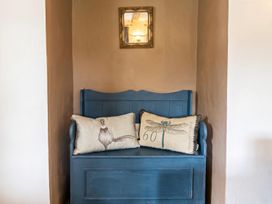 A bench with pillows and a mirror in an entryway at The Old Barn in Manchester