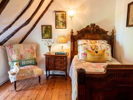 A bedroom with a bed, nightstand, armchair, and artwork on walls at 