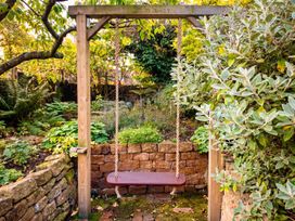 A swing in a garden surrounded by plants and a stone wall at 