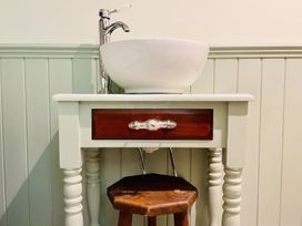 A sink with a wooden drawer and a stool in a bathroom