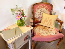 A sitting room with an armchair and a table holding flowers and a notebook